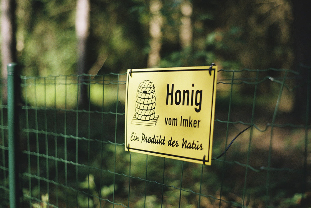Schild Honig vom Imker in grüner Umgebung